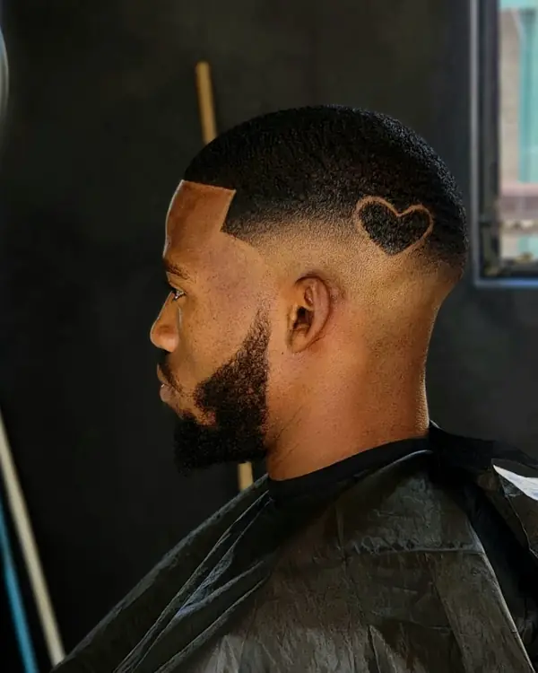 Mid fade con un corazón rasurado sobre la oreja, de perfil
