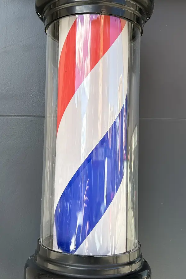 Poste de barbería con franjas rojas, blancas y azules, encendido